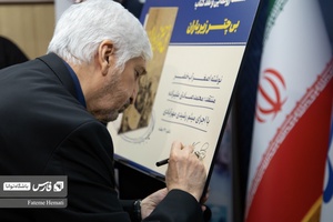 اصغر آب‌خضر نویسنده کتاب پوستر کتاب «بی چتر زیر باران» را امضا میکند