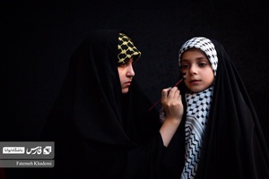 بانویی که در حال نقاشی پرچم فلسطین روی صورت دختر بچه در جشنواره مقاومت است