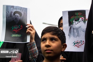 پسر بچه و بانوانی که عکس شهید جمهور را در دست دارند و در مراسم عزاداری شهید رییسی شرکت کرده اند