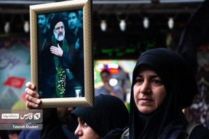 بانویی که در مراسم شهادت آیت الله رییسی عکس ایشان را در دست گرفته است