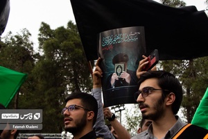 آقایی که عکس شهید آیت الله رییسی را مقابل دانشگاه تهران در دست گرفته