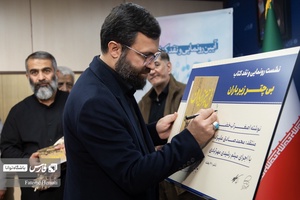 احسان محمدحسنی رئیس سابق  رئیس سازمان سینمایی اوج پوستر یادبود رونمایی کتاب «بی چتر زیر باران» را امضا می کند