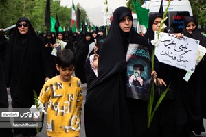 مادری که همراه پسر خود در مراسم شهادت آیت الله رییسی و همراهانش با عکس شهید رییسی در دست،شرکت کرده اند