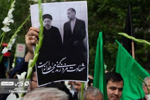عکس شهید جمهور آیت الله رییسی و شهید دیپلمات امیرعبداللهیان در دست مردی که در عزاداری شهادت ایشان شرکت کرده است