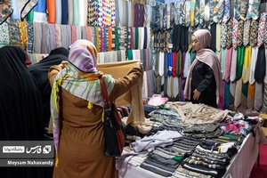 خانم هایی در حال خرید و انتخاب کردن شال و روسری در نمایشگاه شهرخانواده میباشند
