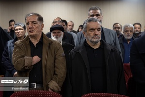 حاضرین به همراه خانواده شهدا و جانبازان دفاع مقدس در حال خواندن سرود ملی ایران در مراسم رونمایی کتاب «بی چتر زیر باران» هستند