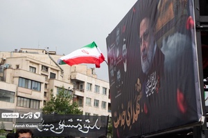 بنر عکس شهدای خدمت به همراه پرچم ایران و پلاکاردی با عنوان رییسی بهشتی شد در مراسم عزاداری شهادت آیت الله رییسی و همراهان ایشان