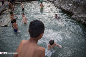 کودکان مشغول آب تنی در چشمه علی هستند. چشمه علی از دیرباز محل آب تنی کودکان در جنوب تهران بوده و قدمت چند صد ساله دارد.