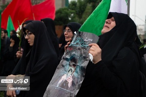 بانویی که در میدان پاستور عکس شهید آیت الله رئیسی را در دست دارد و در حال گریه کردن است