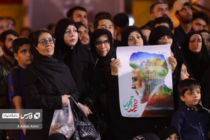 خانمی پلاکارد شهید جمهور را در مراسم‌شام غریبان شهدای خدمت بدست گرفته است