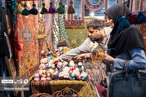خانمی در حال خرید عروسک های سنتی در نمایشگاه شهرخانواده میباشد