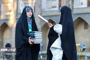 خادمان در حال جمع آوری قرآن ها هستند