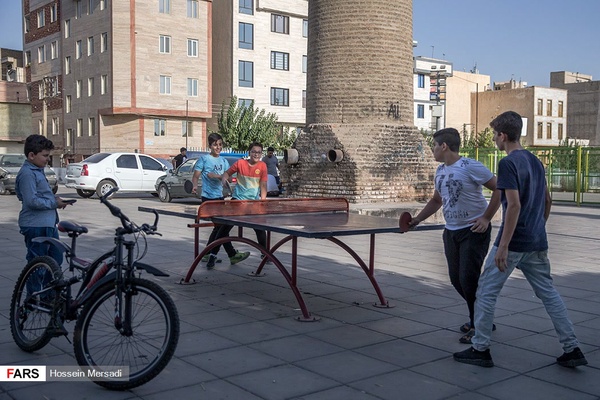 نوجوانان در یکی از زمین های بازی محله دولت آباد مشغول تنیس روی میز هستند. تنیس روی میز یا پینگ پنگ ورزشی است که روی میز انجام می‌شود و دو یا چهار بازیکن در آن مشارکت دارند و هر بازیکن یک راکت دارد و با بهره‌گیری از آن به توپ ضربه می‌زند.
