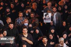 خانمی تصویر شهید رئیسی را در مراسم‌شام غریبان شهدای خدمت بدست گرفته است