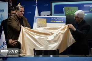 اصغر آب‌خضر  و حاج علی فریدونی در حال رونمایی از پوستر کتاب «بی چتر زیر باران» هستند