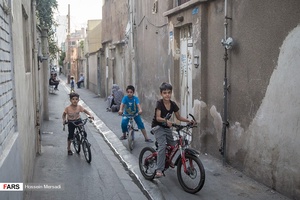 کودکان مشغول دوچرخه سواری در یکی از محله های خیابان طیب. معمولا در محله های پرتراکم جنوب شهر کودکان و نوجوانان در کوچه ها مشغول بازی هستند.
